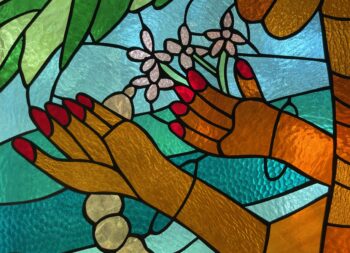 details of a stained glass window featuring hands holding plants